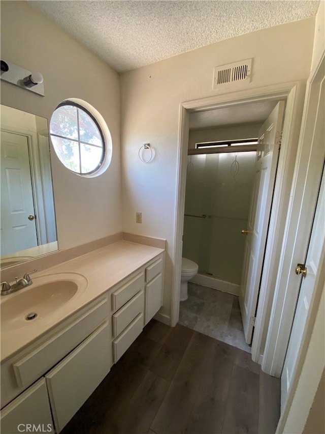 43321 Cottage Ln, Lancaster, CA 93536 - bathroom featuring a textured ceiling, vanity, wood finished floors, a shower stall, and toilet