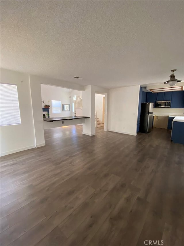 43321 Cottage Ln, Lancaster, CA 93536 - unfurnished living room featuring a textured ceiling, dark wood finished floors, and baseboards