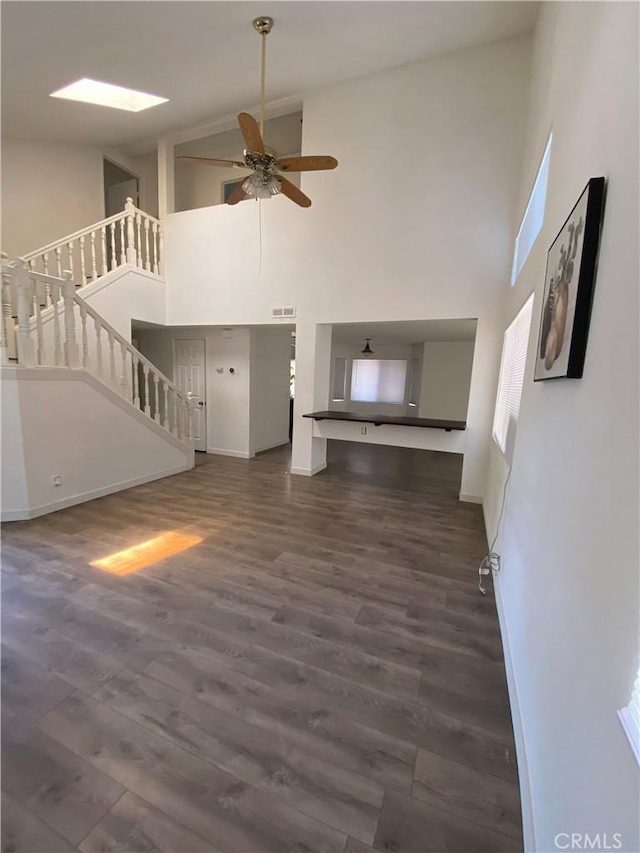 43321 Cottage Ln, Lancaster, CA 93536 - unfurnished living room featuring high vaulted ceiling, stairs, ceiling fan, dark wood finished floors, and baseboards