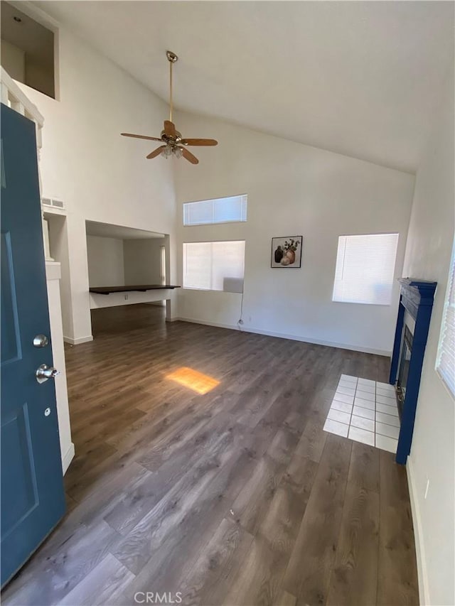 43321 Cottage Ln, Lancaster, CA 93536 - unfurnished living room featuring a ceiling fan, wood finished floors, a glass covered fireplace, high vaulted ceiling, and baseboards