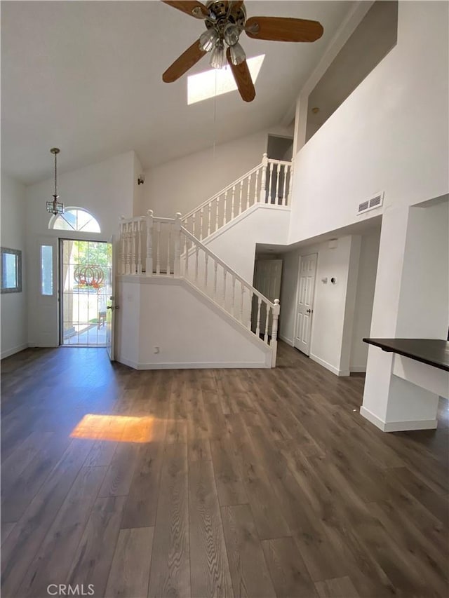 43321 Cottage Ln, Lancaster, CA 93536 - unfurnished living room with high vaulted ceiling, stairway, dark wood-type flooring, ceiling fan, and baseboards