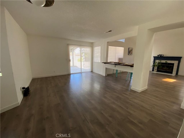 43321 Cottage Ln, Lancaster, CA 93536 - unfurnished living room featuring dark wood-type flooring, a tile fireplace, and a textured ceiling