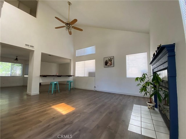 43321 Cottage Ln, Lancaster, CA 93536 - unfurnished living room featuring ceiling fan, high vaulted ceiling, wood finished floors, and a tile fireplace