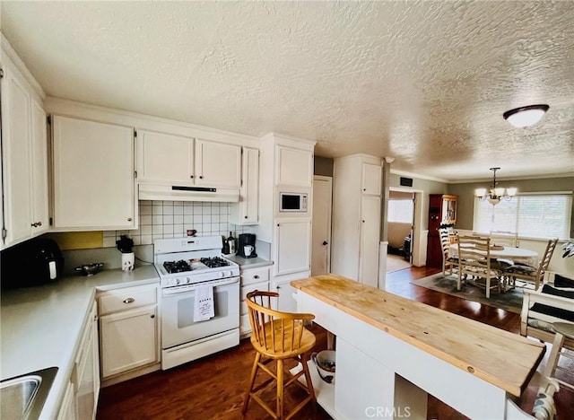 21161 Rancherias Rd, Apple Valley, CA 92307 - kitchen with white appliances, under cabinet range hood, wooden counters, a chandelier, and dark wood-type flooring