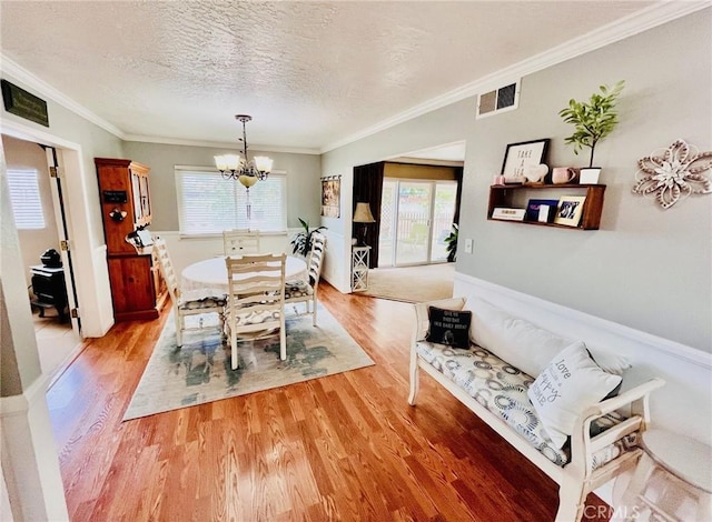 21161 Rancherias Rd, Apple Valley, CA 92307 - dining area featuring a chandelier, light wood-style floors, ornamental molding, and a textured ceiling