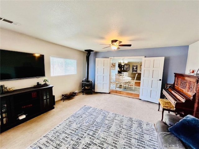 21161 Rancherias Rd, Apple Valley, CA 92307 - carpeted living area featuring a wood stove, ceiling fan, baseboards, and a chandelier