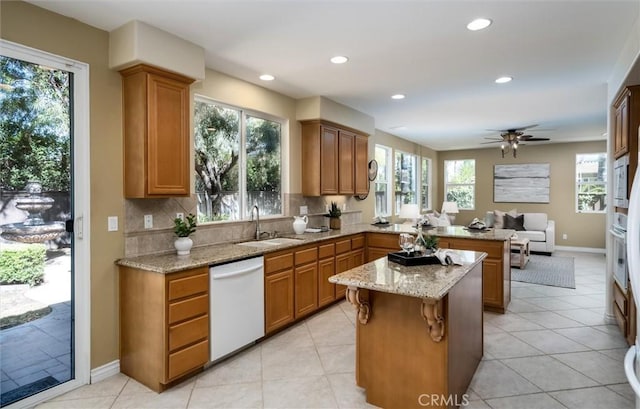 44035 Cindy Cir, Temecula, CA 92592 - kitchen featuring dishwasher, a peninsula, brown cabinets, light stone counters, and backsplash