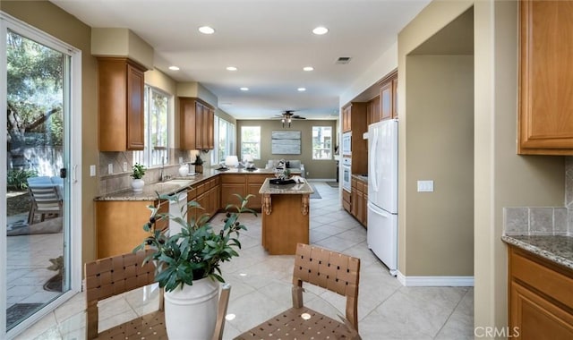 44035 Cindy Cir, Temecula, CA 92592 - kitchen with freestanding refrigerator, brown cabinetry, tasteful backsplash, plenty of natural light, and recessed lighting