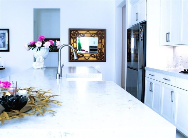 11986 Sagecrest Ct, Corona, CA 92883 - kitchen with freestanding refrigerator, light stone countertops, white cabinets, and a sink