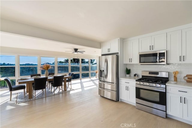 1748 Prince Albert Dr, Riverside, CA 92507 - kitchen with appliances with stainless steel finishes, decorative backsplash, light countertops, light wood-type flooring, and white cabinets