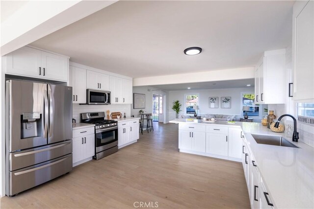 1748 Prince Albert Dr, Riverside, CA 92507 - kitchen featuring appliances with stainless steel finishes, a sink, backsplash, and white cabinetry