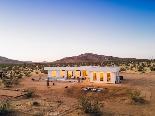 2600 Sunny Vista Rd, Joshua Tree, CA 92252 - back of house at dusk featuring a mountain view, stucco siding, and a patio