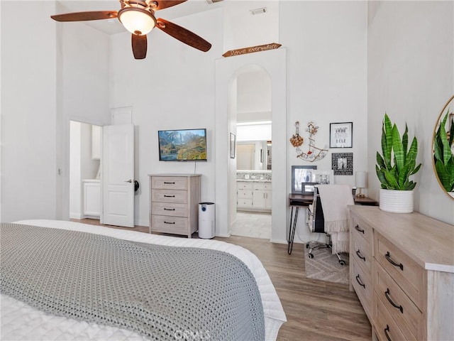 13290DR Country Club Dr, Victorville, CA 92395 - bedroom with a high ceiling, light wood finished floors, arched walkways, ensuite bath, and a ceiling fan