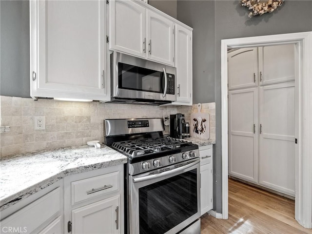 13290DR Country Club Dr, Victorville, CA 92395 - kitchen featuring stainless steel appliances, white cabinets, tasteful backsplash, light wood finished floors, and light stone countertops