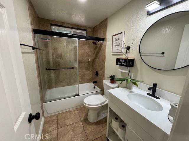 3400 Glasgow Cir, Riverside, CA 92503 - full bathroom with vanity, combined bath / shower with glass door, toilet, and tile patterned flooring