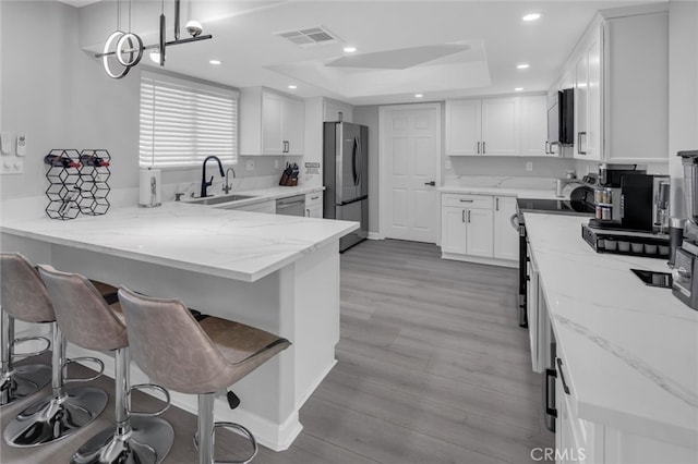31780 Sierra Del Sol, Thousand Palms, CA 92276 - kitchen with stainless steel appliances, a sink, a peninsula, a tray ceiling, and white cabinetry