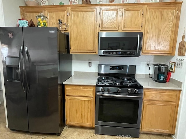24967 Volga St, Hemet, CA 92544 - kitchen featuring gas stove, refrigerator with ice dispenser, stainless steel microwave, light countertops, and light tile patterned flooring
