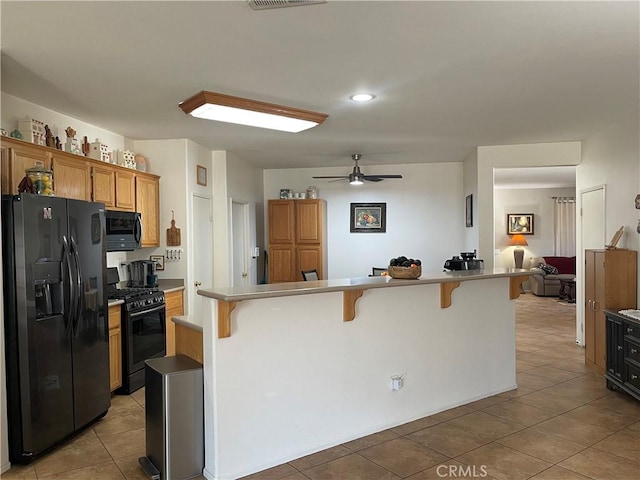 24967 Volga St, Hemet, CA 92544 - kitchen with black appliances, a kitchen breakfast bar, light tile patterned floors, open floor plan, and a ceiling fan