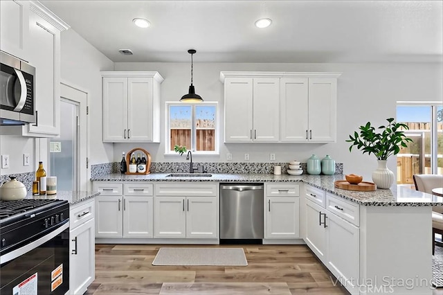 428 Oleander Ct, Chowchilla, CA 93610 - kitchen featuring appliances with stainless steel finishes, a sink, a peninsula, white cabinetry, and light wood finished floors
