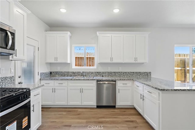 428 Oleander Ct, Chowchilla, CA 93610 - kitchen featuring stainless steel appliances, a peninsula, white cabinets, recessed lighting, and light wood finished floors