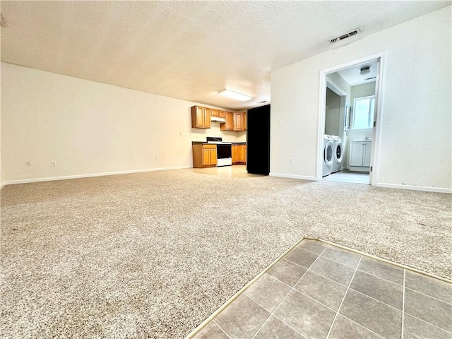1170 Hobart St, Chico, CA 95926 - unfurnished living room featuring independent washer and dryer, light colored carpet, a textured ceiling, baseboards, and light tile patterned floors