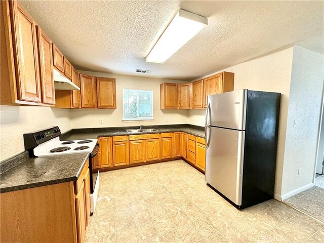 1170 Hobart St, Chico, CA 95926 - kitchen with freestanding refrigerator, range with electric stovetop, under cabinet range hood, dark countertops, and a textured ceiling