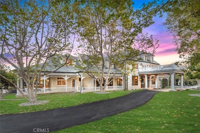 10 Strawberry Ln, San Juan Capistrano, CA 92675 - back of property at dusk featuring covered porch, stone siding, a yard, and a balcony