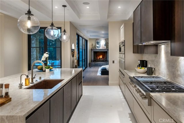 10 Strawberry Ln, San Juan Capistrano, CA 92675 - kitchen featuring a sink, a lit fireplace, dark brown cabinetry, backsplash, and recessed lighting