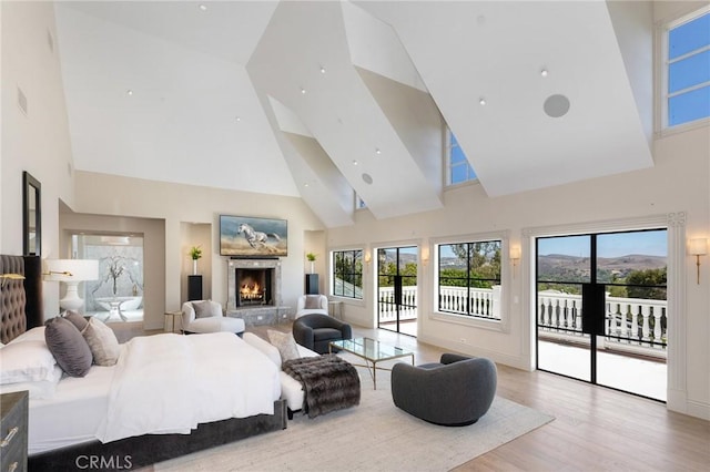 10 Strawberry Ln, San Juan Capistrano, CA 92675 - bedroom featuring high vaulted ceiling, access to exterior, wood finished floors, a lit fireplace, and multiple windows