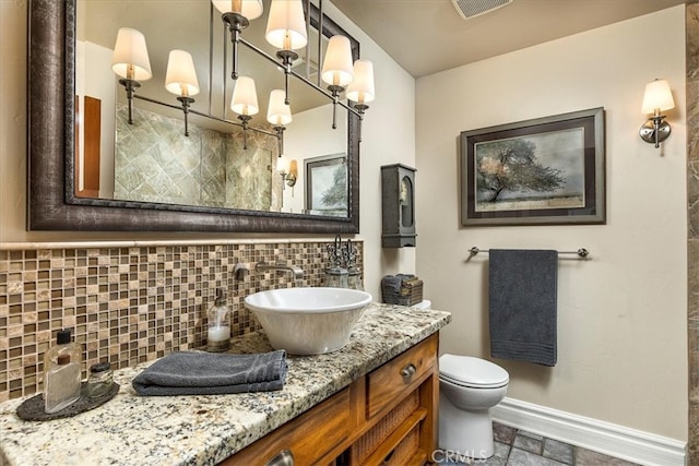 30026 Santiago Rd, Temecula, CA 92592 - bathroom with tasteful backsplash, toilet, vanity, baseboards, and stone finish floors