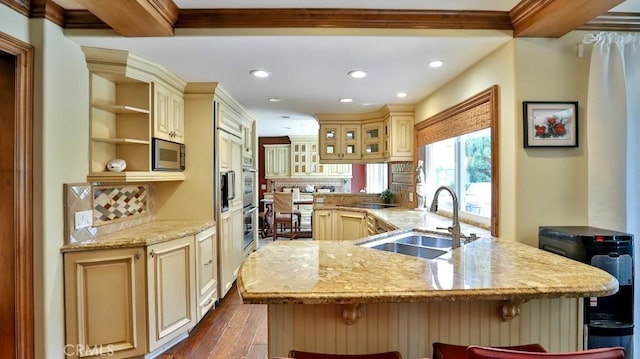 21822 Seacrest Ln, Huntington Beach, CA 92646 - kitchen featuring cream cabinets, a sink, dark wood-style flooring, a breakfast bar, and tasteful backsplash
