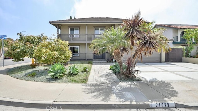 21822 Seacrest Ln, Huntington Beach, CA 92646 - view of front of property featuring driveway, stucco siding, an attached garage, a balcony, and covered porch