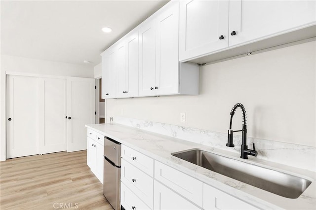27130 Blue Hill Dr, Menifee, CA 92586 - kitchen with a sink, freestanding refrigerator, white cabinetry, light stone countertops, and light wood-type flooring