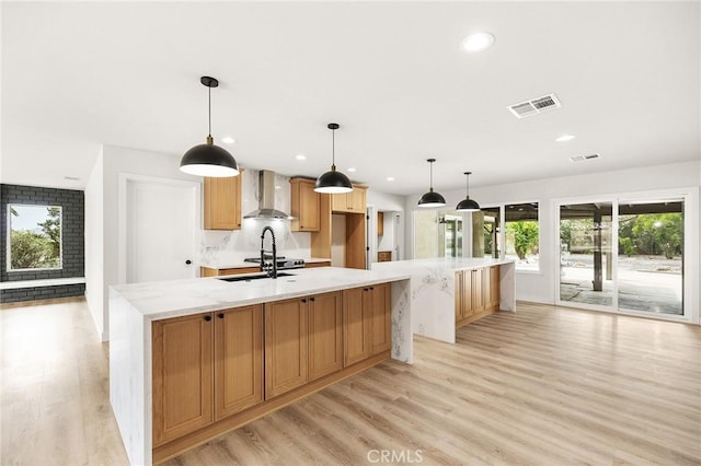 27130 Blue Hill Dr, Menifee, CA 92586 - kitchen featuring wall chimney exhaust hood, a large island with sink, light wood-style flooring, recessed lighting, and a sink