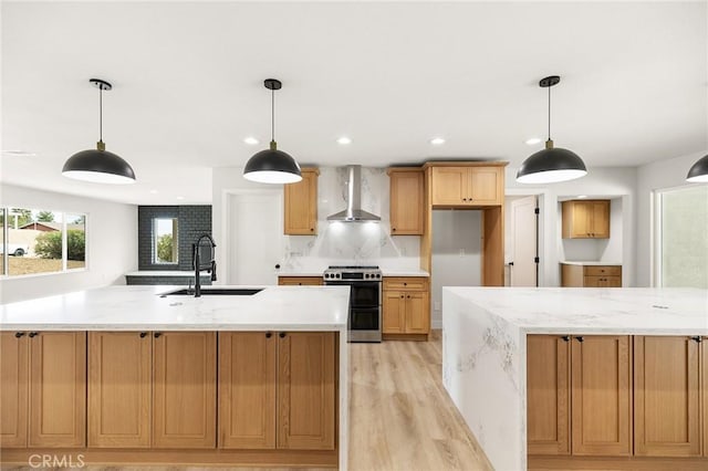 27130 Blue Hill Dr, Menifee, CA 92586 - kitchen featuring stainless steel stove, wall chimney exhaust hood, a sink, light wood-style floors, and a large island with sink