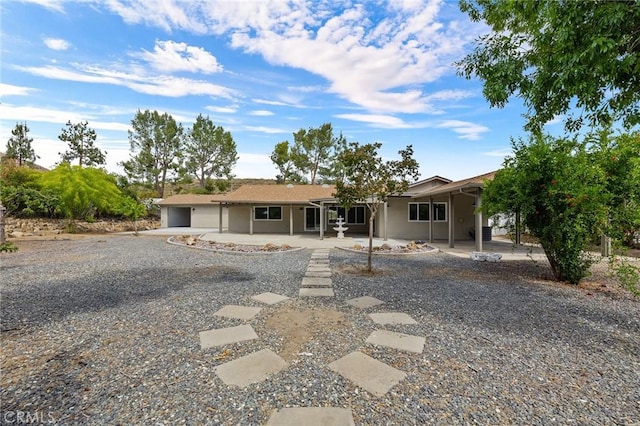 27130 Blue Hill Dr, Menifee, CA 92586 - rear view of house featuring gravel driveway, a patio area, and a garage