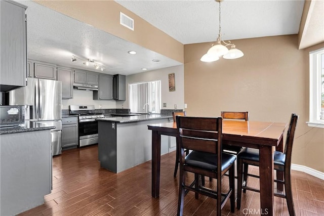 11941 9th Ave, Hesperia, CA 92345 - kitchen with appliances with stainless steel finishes, a textured ceiling, a chandelier, a peninsula, and under cabinet range hood