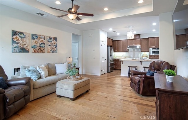 67 Galan St, Rancho Mission Viejo, CA 92694 - living room with light wood-style floors, ceiling fan, recessed lighting, and a tray ceiling