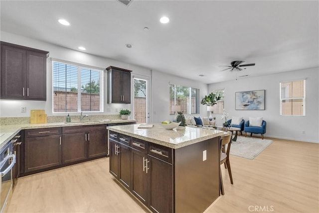 719 Huron Pl, Claremont, CA 91711 - kitchen featuring light wood-type flooring, dark brown cabinetry, a kitchen island, light stone counters, and recessed lighting