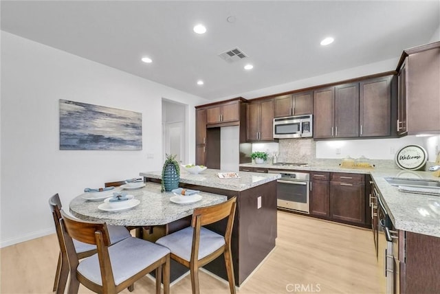 719 Huron Pl, Claremont, CA 91711 - kitchen with appliances with stainless steel finishes, light wood-style floors, light stone counters, dark brown cabinets, and recessed lighting