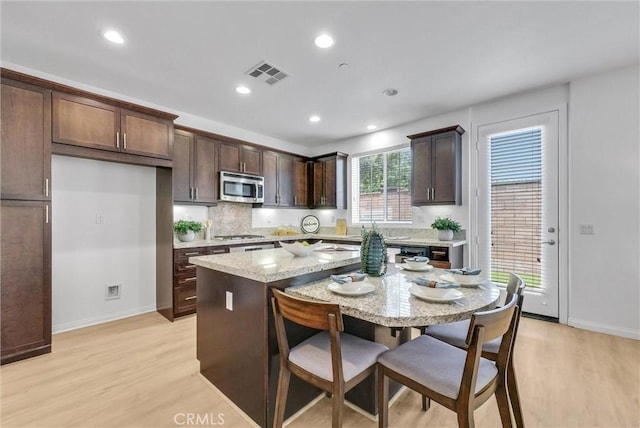 719 Huron Pl, Claremont, CA 91711 - kitchen featuring stainless steel appliances, light wood-type flooring, dark brown cabinetry, a breakfast bar area, and light stone countertops