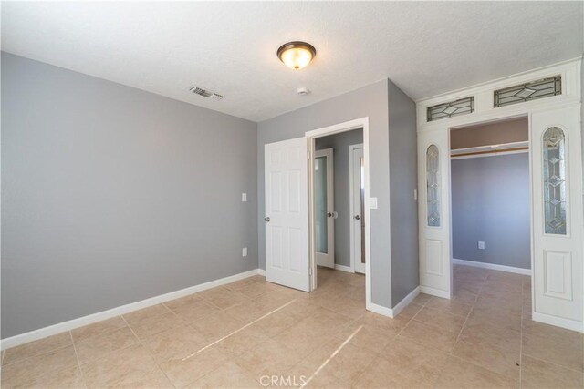 11314 Mariposa Rd, Hesperia, CA 92345 - unfurnished bedroom with baseboards, light tile patterned floors, a textured ceiling, and a closet