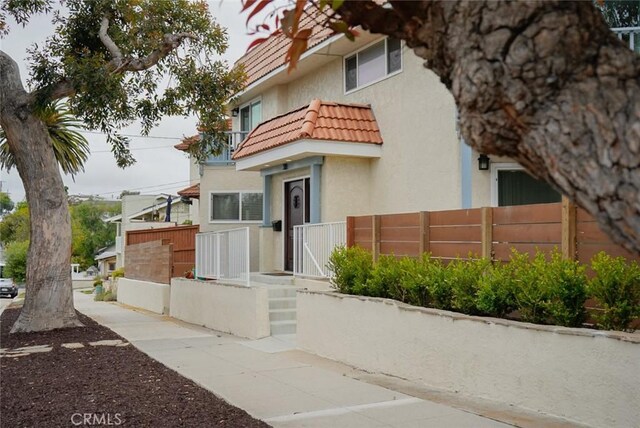 318 S Lucia Ave, Redondo Beach, CA 90277 - view of front of house with stucco siding, a tile roof, a balcony, and a gate