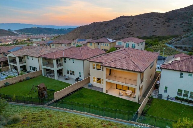 18814 Annmae Pl, Saugus, CA 91350 - back of house at dusk featuring a fenced backyard, a balcony, a mountain view, and a patio