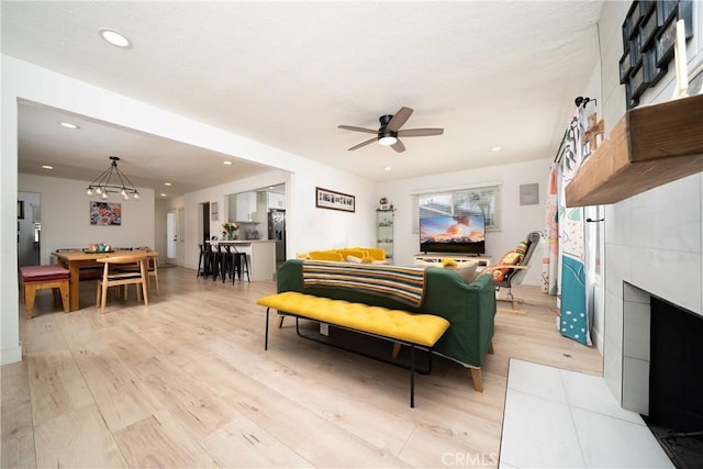 9966 Vernon Ave, Montclair, CA 91763 - living area with light wood finished floors, ceiling fan, a tile fireplace, recessed lighting, and a chandelier