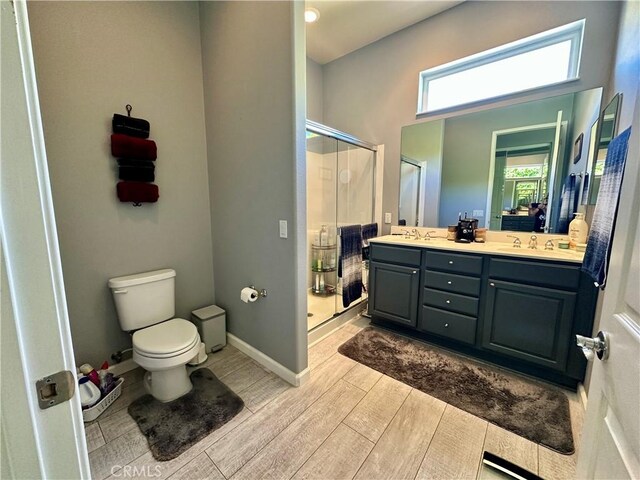 5836 Indian Canyon Dr, Banning, CA 92220 - full bathroom featuring wood finished floors, toilet, a shower stall, double vanity, and baseboards