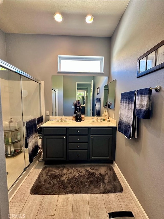 5836 Indian Canyon Dr, Banning, CA 92220 - bathroom featuring a shower stall, double vanity, wood finished floors, and baseboards