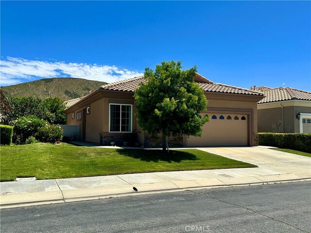 5836 Indian Canyon Dr, Banning, CA 92220 - view of front facade featuring a garage, a tiled roof, stucco siding, and a front lawn