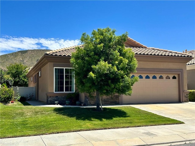 5836 Indian Canyon Dr, Banning, CA 92220 - mediterranean / spanish home featuring a tiled roof, a garage, concrete driveway, stone siding, and stucco siding