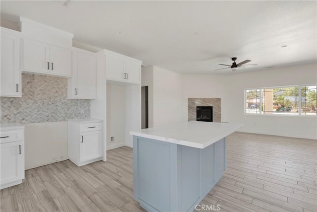22212 Lone Eagle Rd, Apple Valley, CA 92308 - kitchen featuring ceiling fan, light wood-type flooring, a kitchen island, decorative backsplash, and white cabinets